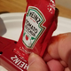 Placing a ketchup packet into the mouth of the Heinz Packet Roller